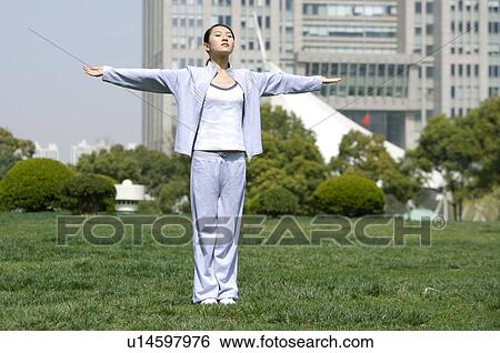Young woman standing with arms outstretched on lawn View Large Photo Image Stock Photograph - Young woman standing with arms outstretched on lawn. Fotosearch