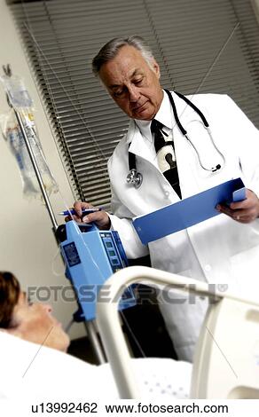 Doctor looking at patient chart View Large Photo Image Stock Image - Doctor looking at patient chart . Fotosearch