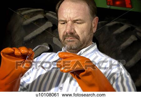 Stock Image - Man putting on safety glasses. Fotosearch