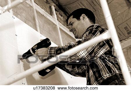 Stock Photo - Man putting up drywall. Fotosearch