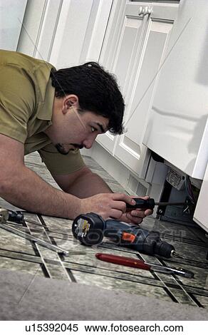 Stock Photography - Man repairing dishwasher. Fotosearch