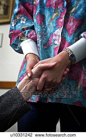 Stock Image - Nurse holding senior womans hand. Fotosearch
