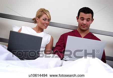 Couple in bed working on laptop computers View Large Photo Image Picture - Couple in bed working on laptop computers. Fotosearch