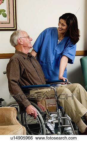 Stock Photograph - Man in wheelchair with nurse. Fotosearch