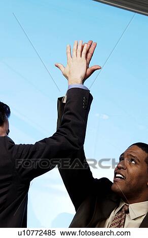 Stock Photography - Two businessman giving each other high five. Fotosearch