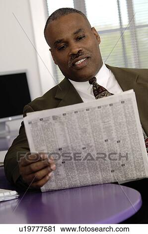 Stock Image - African American businessman reading newspaper. Fotosearch