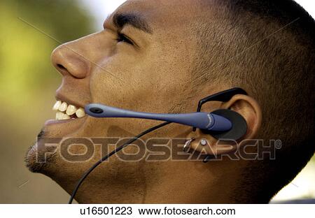 Stock Image - African American man talking on cell phone with hands free head . Fotosearch