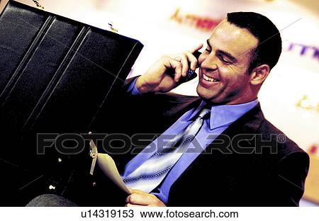 Stock Image - Businessman on cell phone with briefcase. Fotosearch