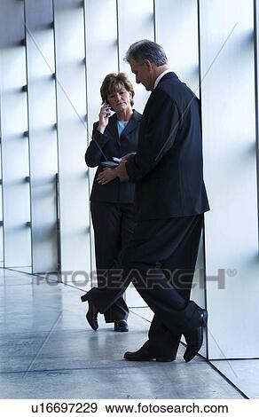 Businesswoman on cell phone while businessman is waiting View Large Photo Image Stock Photo - Businesswoman on cell phone while businessman is waiting. Fotosearch
