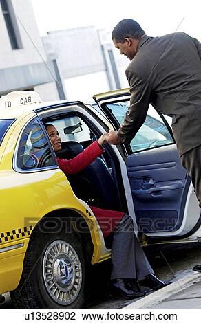 Stock Image - Couple getting out of cab. Fotosearch