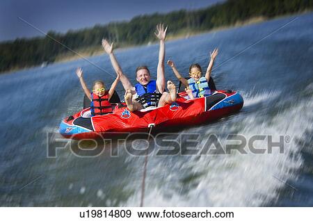 Stock Photo - Dad with kids on inner tube. Fotosearch