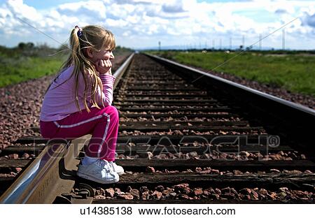 Stock Photo - Girl sitting on railroad tracks. Fotosearch