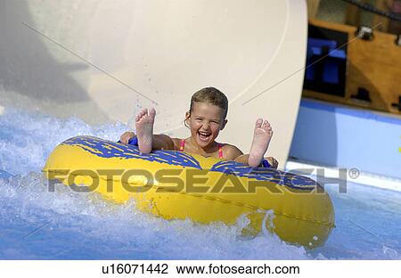 Stock Image - Kid going down water slide on a tube. Fotosearch