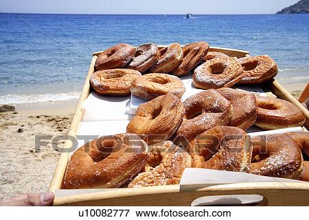 Stock Photo - A tray of donuts on the beach. Fotosearch