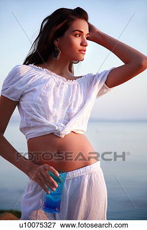 Woman in white outfit with sea behind her View Large Photo Image Stock Photo - Woman in white outfit with sea behind her. Fotosearch