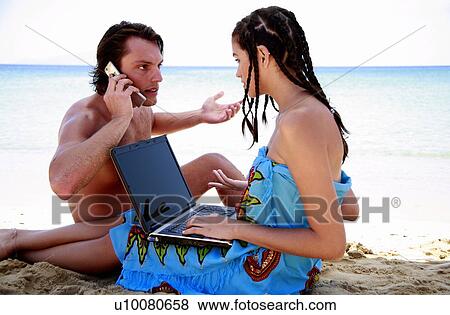 Young couple on beach with laptop and cell phone View Large Photo Image Stock Photo - Young couple on beach with laptop and cell phone. Fotosearch