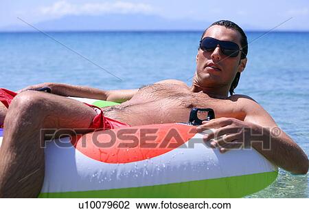 Young man in water on inflatable life ring View Large Photo Image Stock Image - Young man in water on inflatable life ring. Fotosearch