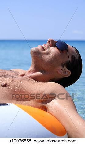 Stock Photography - Young man in water on inflatable life ring. Fotosearch
