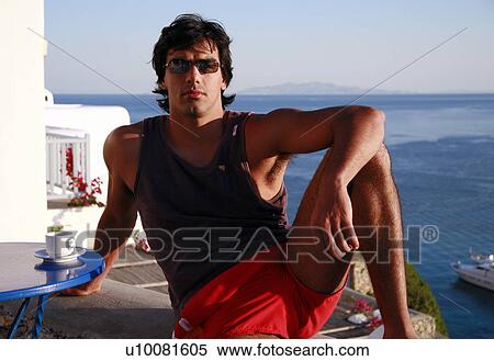 Young man sitting on balcony with a view View Large Photo Image Stock Photography - Young man sitting on balcony with a view. Fotosearch