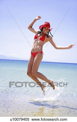 Young woman in bikini and hat jumping in the air View Large Photo Image Stock Photography - Young woman in bikini and hat jumping in the air. Fotosearch
