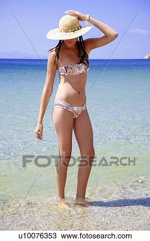 Young woman in bikini and hat on beach View Large Photo Image Stock Image - Young woman in bikini and hat on beach. Fotosearch