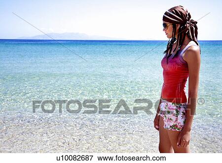 Young woman on beach looking out to the water View Large Photo Image Stock Photo - Young woman on beach looking out to the water. Fotosearch