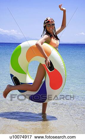 Young woman on beach with inflatable life ring View Large Photo Image Stock Photo - Young woman on beach with inflatable life ring. Fotosearch