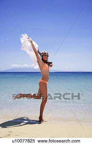 Young woman running on beach holding pareo View Large Photo Image Stock Photography - Young woman running on beach holding pareo. Fotosearch