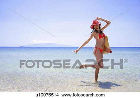 Picture - Young woman with bikini, hat, and beach bag. Fotosearch