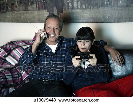 Stock Photo - Grandfather and granddaughter watching television. Fotosearch