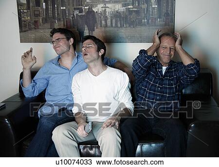Three men watching a game on television View Large Photo Image Stock Image - Three men watching a game on television. Fotosearch