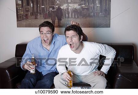 Two men watching a game on television View Large Photo Image Stock Image - Two men watching a game on television. Fotosearch