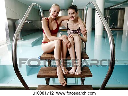 Stock Image - Two young woman sitting next to spa pool. Fotosearch