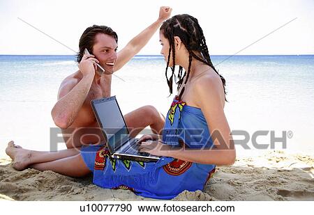 Young couple on beach with laptop and cell phone View Large Photo Image Stock Image - Young couple on beach with laptop and cell phone. Fotosearch