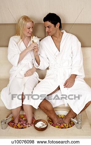 Stock Photo - A young couple enjoying a foot bath with rose petals. Fotosearch