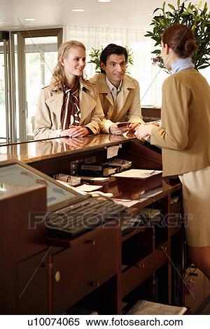 Couple checking in at hotel reception View Large Photo Image Stock Photography - Couple checking in at hotel reception. Fotosearch