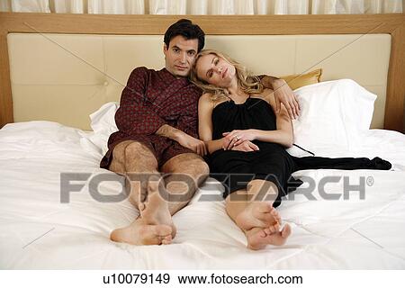 Couple relaxing in bed View Large Photo Image Stock Photo - Couple relaxing in bed. Fotosearch