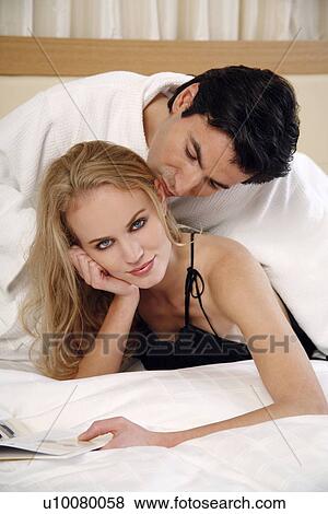Couple relaxing in bed View Large Photo Image Stock Photo - Couple relaxing in bed. Fotosearch