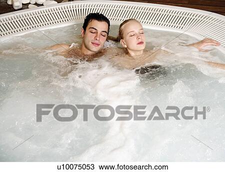 Stock Image - One man with one woman in jacuzzi at a spa. Fotosearch
