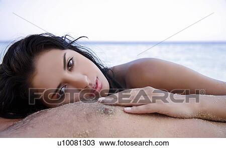 Stock Image - Young woman on man's chest on beach. Fotosearch