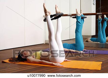 Stock Image - Two young women performing a pilates exercise. Fotosearch