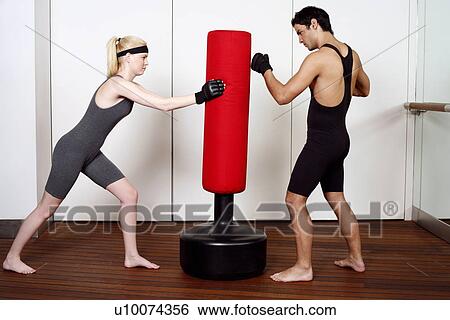 Young man and woman practicing with a punching bag View Large Photo Image Stock Photograph - Young man and woman practicing with a punching bag. Fotosearch