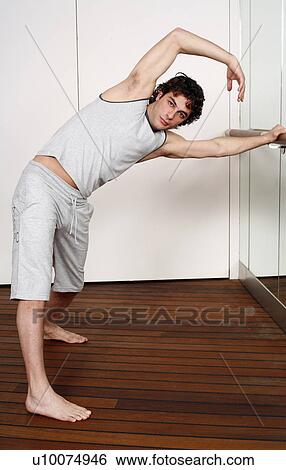 Stock Photograph - Young man stretching in gym. Fotosearch