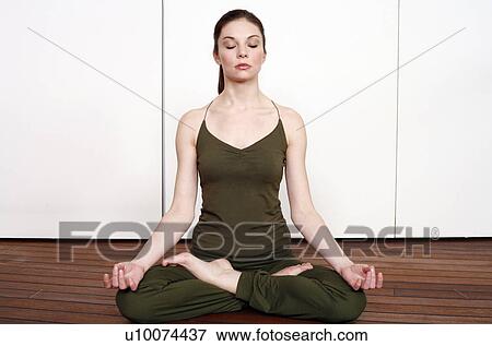 Young woman in a fitness class meditating View Large Photo Image Stock Photo - Young woman in a fitness class meditating. Fotosearch