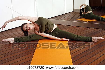 Stock Image - Young woman performing a pilates stretch. Fotosearch