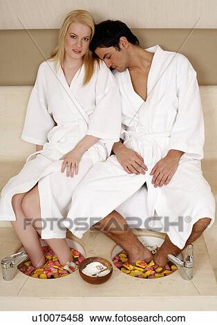 Stock Photo - A young couple enjoying a foot bath with rose petals. Fotosearch