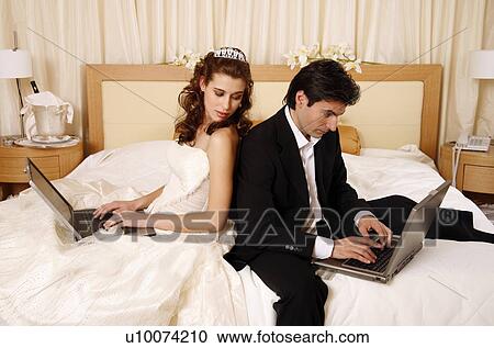 Stock Image - Bride and groom on laptops. Fotosearch