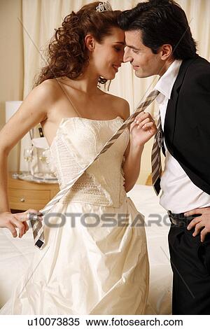 Stock Photography - Bride pulling groom's tie off in hotel room. Fotosearch