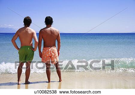 Two men on the beach looking out to sea View Large Photo Image Stock Photo - Two men on the beach looking out to sea. Fotosearch