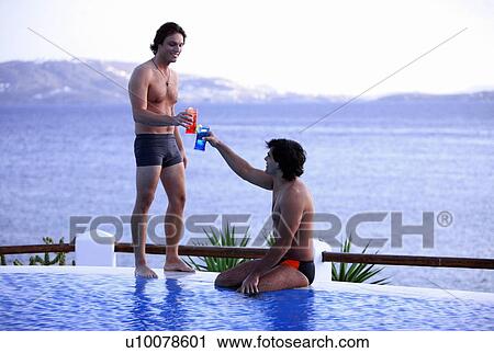 Two men toasting with cocktails by the poolside View Large Photo Image Stock Image - Two men toasting with cocktails by the poolside. Fotosearch